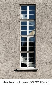 high vertical window behind which flights of stairs are visible