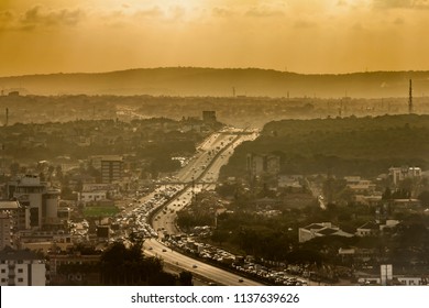 High View Point Hazy Cityscape Of Accra, Ghana. Traffic Jam On George Bush Highway With Hills On The Background