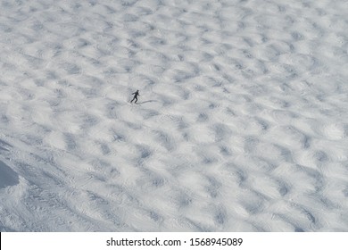 High Views Of A Mogul Run At A Ski Resort In The Winter. A Lone Skier Can Be Seen In The Distance.