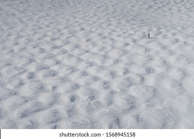 High Views Of A Mogul Run At A Ski Resort In The Winter. A Lone Skier Can Be Seen In The Distance.