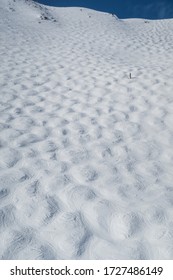 High Views Of A Mogul Run At A Ski Resort In The Winter. A Lone Skier Can Be Seen In The Distance.