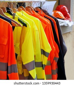 High visibility jackets on a hanger with protective helmets behind, in a work clothes store .