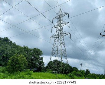 High voltage lines and power pylons in a flat and green agricultural landscape on a sunny day with clouds in the blue sky - Shutterstock ID 2282179943