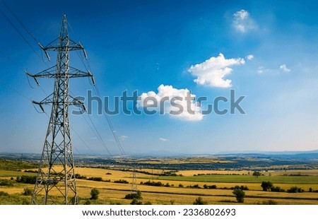 High voltage power electricity polls and lines in agricultural fields close to Balkan mountains in central Bulgaria