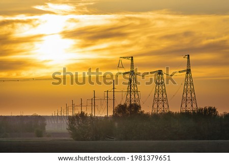 High voltage power line on industrial electricity line tower for electrification rural countryside. Energy transmisson with overhead power line