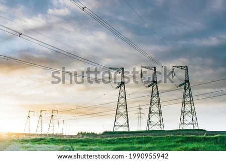 High voltage power line on industrial electricity line tower for electrification rural countryside at sunset