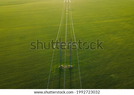 High voltage power line on industrial electricity line tower for electrification rural countryside. Energy transmisson with overhead power line