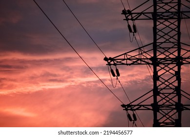 High voltage power lines pylons and electrical cables against the backdrop of a bright colorful sunset sky. Modern infrastructure of high voltage transmission lines. Overhead power lines. Electricity
