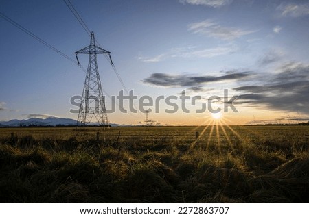 High voltage power pylon towers and powerlines at sunrise, Canterbury, South Island