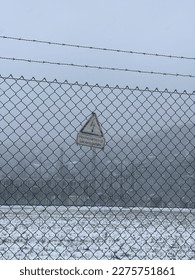 High voltage sign in the snow on the fence of the factory in winter - Shutterstock ID 2275751861