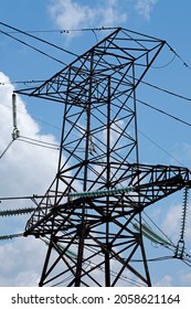 High Voltage Tower Against Blue Sky Bottom View. Power Line. Transmission Tower Close-up. Metallic High Voltage Direct Current Line. 