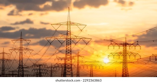 high voltage towers with power line grid for transmission of electricity, beautiful industrial landscape with bright sunset light in Germany, Europe - Powered by Shutterstock