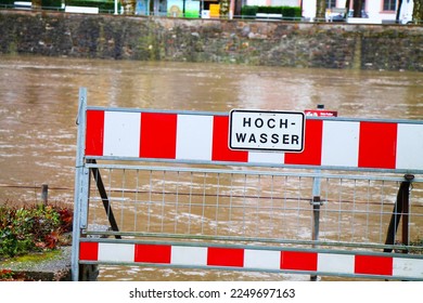 High water warning street sign in germany. Spa town embankment under water. High water warning sign, red and white flood barrier.  - Shutterstock ID 2249697163