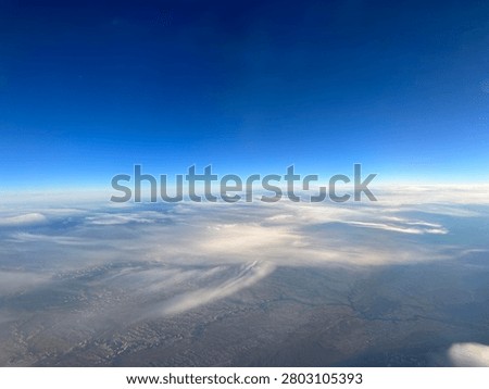 High-Altitude Airplane Window View of Clouds Over Desert Terrain