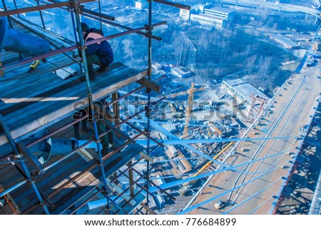 High-altitude work. Construction of the bridge. Workers on scaffolding.