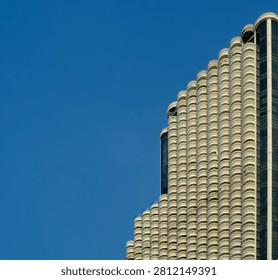 A high-angle architectural shot featuring rows of curved white balconies on a luxury tall building against a solid blue sky.