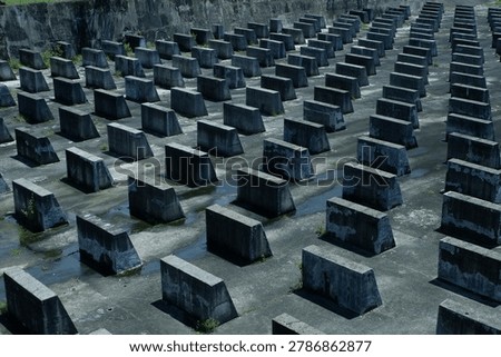 A high-angle architectural shot of a patterned grid of concrete baffle blocks on a spillway floor, showcasing industrial infrastructure design for engineering stock photography.