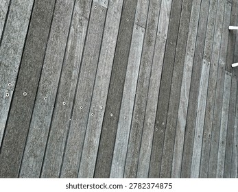 High-angle background texture of weathered grey wooden planks secured with visible metal screws.