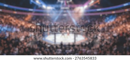 A high-angle, blurred shot of a large, crowded arena, featuring a central fighting ring illuminated by vibrant spotlights, creating an energetic atmosphere.