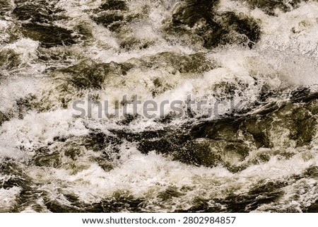 High-angle close-up of heavy, multi-tiered river currents folding over a submerged rock ledge in the Jinsha River at Tiger Leaping Gorge, Yunnan Province, China. Dense olive-green waters surge relentlessly across the hidden shelf, breaking into successive, rolling walls of bright white foam and aggressive surface spray. Captures the immense liquid volume and unstoppable kinetic momentum of East Asia's deepest mountain canyon passes.