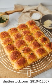 A high-angle close-up shot captures a square pan of freshly baked, buttery pull-apart garlic rolls topped with flaky salt and parsley