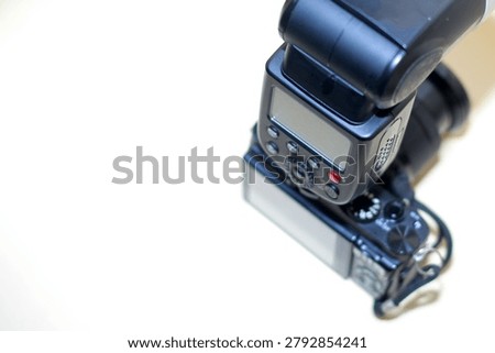 a high-angle, close-up shot of an external speedlight flash unit mounted onto the hot shoe of a digital camera body