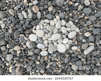 High-angle close-up showcasing an assortment of smooth pebble stones arranged closely together. The stones display a range of gray tones and soft textures, suitable for backgrounds