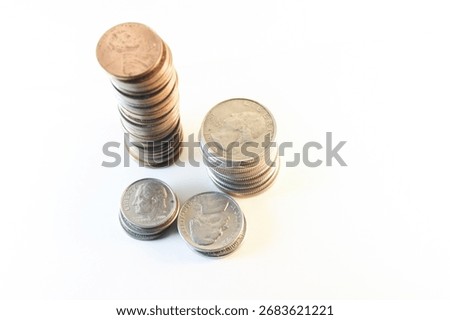 A high-angle, close-up studio shot featuring multiple stacks of United States coins: Pennies, Quarters, Dimes and Half Dollars on White Background