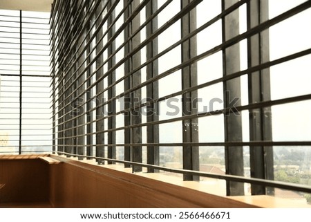 A high-angle close-up view of a modern window with a metal grille, showcasing a wooden sill