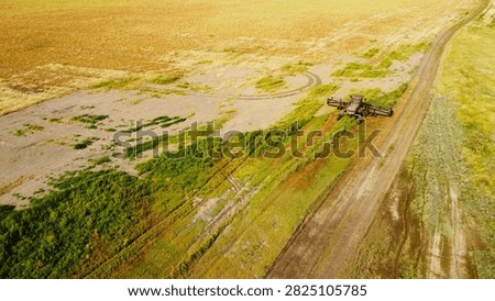 A high-angle drone photograph capturing a self-propelled windrower swather from directly above as it cuts through dense green vegetation in a field.