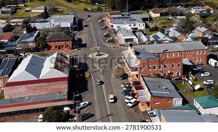 A high-angle drone shot captures the quiet streets, shops, and roundabout of Dorrigo.