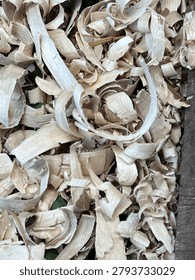 High-angle full-frame background texture of natural light brown wood shavings and wood curls from carpentry work.