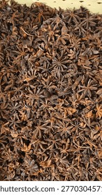 A high-angle, full-frame shot of a collection of dried star anise seeds. The image highlights the natural brown texture, star-shaped patterns, and organic details of this aromatic spice. Suitable for food industry, herbal medicine, or culinary background themes.