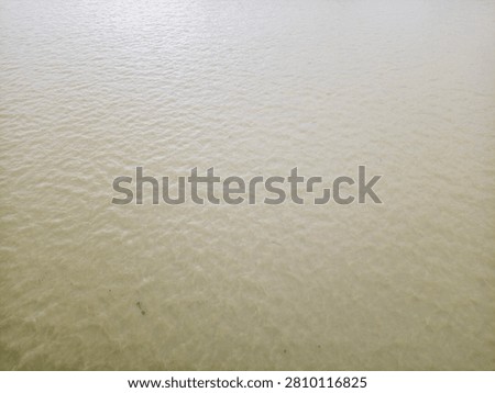 A high-angle, full-frame view of turbid, muddy brown water with gentle ripples on the surface, suitable for environmental, weather, or texture backgrounds.