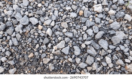 High-angle, monochromatic view of small,irregular gray and white crushed gravel or aggregate, creating a dense, rough natural texture.