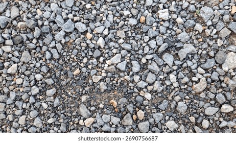 High-angle, monochromatic view of small,irregular gray and white crushed gravel or aggregate, creating a dense, rough natural texture.