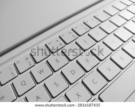 High-angle monochrome macro view of a white laptop QWERTY keyboard layout, focusing on key details, modern typography, and clean computer hardware design.