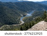 A high-angle panoramic perspective of a river snaking through a steep, green mountain valley.