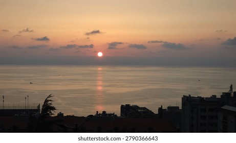 High-angle panoramic view of a golden sunset over the Mediterranean sea, with city building silhouettes in Beirut, Lebanon.
Breathtaking twilight seascape with a setting sun reflecting on the water surface above urban coastal rooftops.