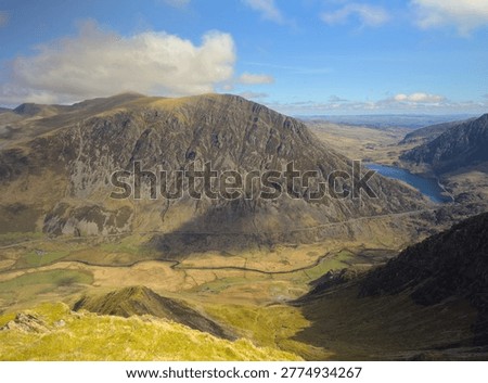 A high-angle panoramic view overlooking the dramatic glacial valley of Nant Ffrancon and the peak of Pen yr Ole Wen. Shot from the rocky summit of Y Garn in the Glyderau range of Eryri Snowdonia National Park, North Wales