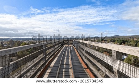 A high-angle perspective of a timber bridge path leading toward a scenic Australian landscape.