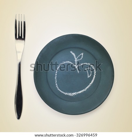high-angle shot of a fork and a plate painted as a chalkboard with an apple drawn with chalk in it on a beige surface