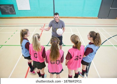 High-angle Shot Of Gym Teacher With A Netball Talking To High School Students In A Gym.