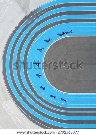 High-angle shot of multiple people inline skating on a bright blue circular track with white lines, showcasing speed and dynamic movement.