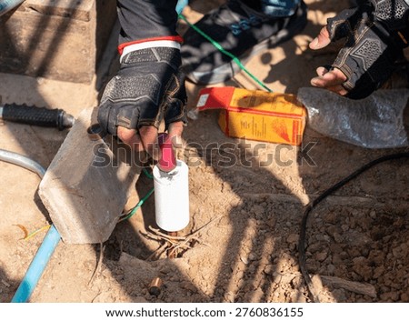 High-angle shot of a professional installer performing an exothermic weld (cadweld) to bond a grounding cable to a copper rod.