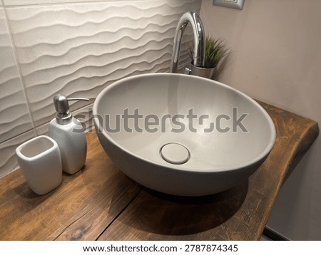 High-angle shot of a round ceramic basin on a wooden vanity with bathroom accessories