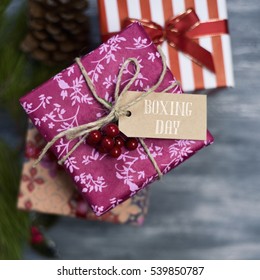 Happy Boxing Day Messages, Wishes, Quotes, And Images 44 high-angle shot of some cozy gifts wrapped in different nice papers and tied with ribbons and strings of different colors, with a paper tag tied to one of them with the text boxing day