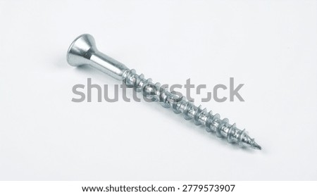 A high-angle studio shot of a single silver-colored metal wood screw with a countersunk head, isolated on a clean white background.