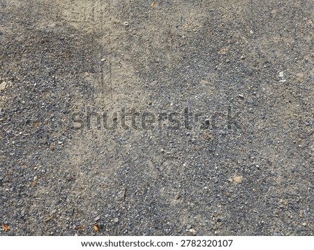 High-angle texture background of a rough dirt road mixed with small gravel and pebbles.