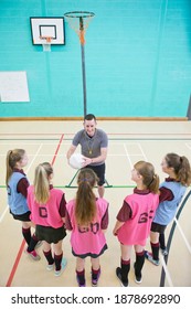 High-angle Vertical Shot Of Gym Teacher With A Netball Talking To High School Students In A Gym.